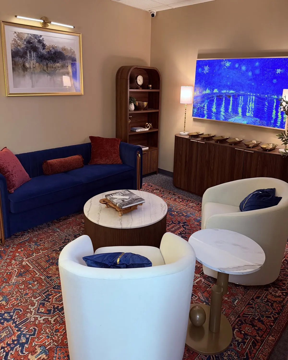 The Sip & Scent Lounge: a navy velvet sofa, cream armchairs and marble side tables on a red Persian rug
